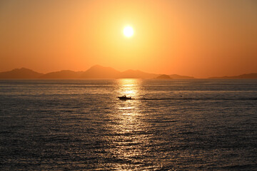 On a sunset evening, the sight of a boat sailing while feeling the light of the sunset