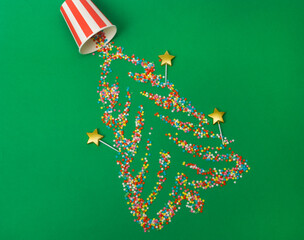 Christmas background. Sugar stars scattered across a green background in the shape of a Christmas tree. Top view, flat lay