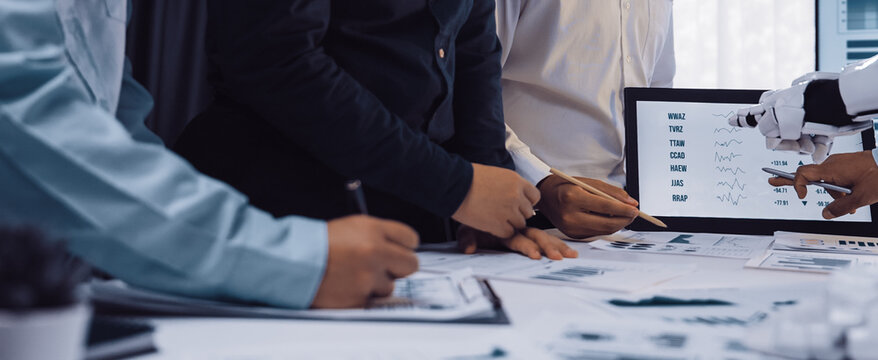 A dynamic scene capturing business professionals collaborating in an office with advanced technology. The use of a robotic arm emphasizes innovation and efficiency.Noogenesis