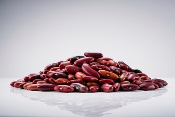 A pile of kidney beans on a white reflective surface against a light gray gradient background