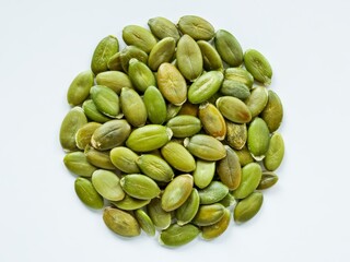 A close up shot of a pile of green pumpkin seeds on a white surface in a studio setting for food photography