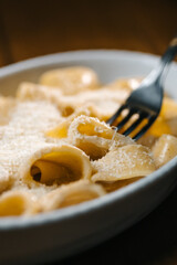 Fork lifting creamy pasta with grated parmesan in a white dish