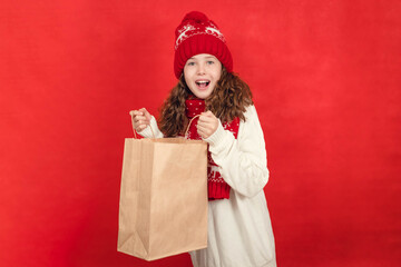 Happy teenage girl holding a paper bag in her hands and rejoicing in gifts, black friday, new year,...
