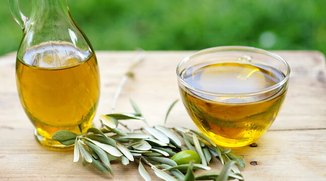 Olive oil bottle on wooden table at green background