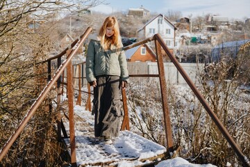 A stylish 12-year-old teenage girl walks through a picturesque winter field. Authentic moment of seasonal beauty, youthful elegance and natural winter exploration