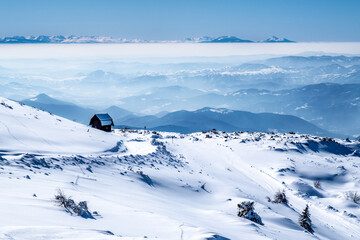Mountain cabin with the view on mountain ranges under the snow, fog and clouds, mountain Kopaonik, Serbia