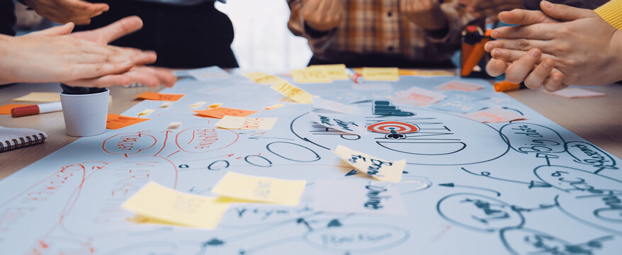 Energetic team collaboration session captured with hands in motion over a detailed mind map. Colorful sticky notes ignite creative discussions in a vibrant workspace. SACTR