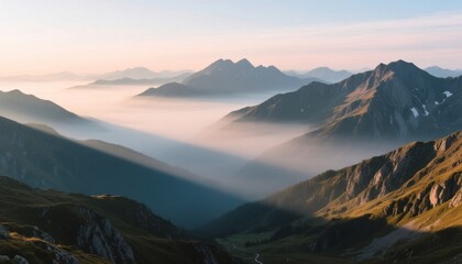 Layered mountain range landscape with valley fog illuminated by soft morning sun rays