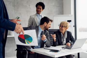 A group of business professionals is attending a presentation given by a colleague in a modern office or meeting room