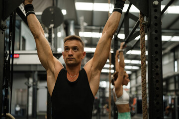 Man and woman training pull ups in gym
