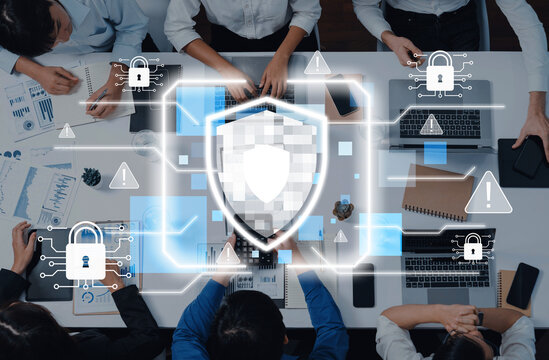 A group of professionals collaborates at a modern office table, focusing on cybersecurity strategy, as digital security icons and a shield graphic enhance the scene. Trope