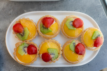 Colorful fruit tarts arranged neatly on a white platter for a delightful dessert experience