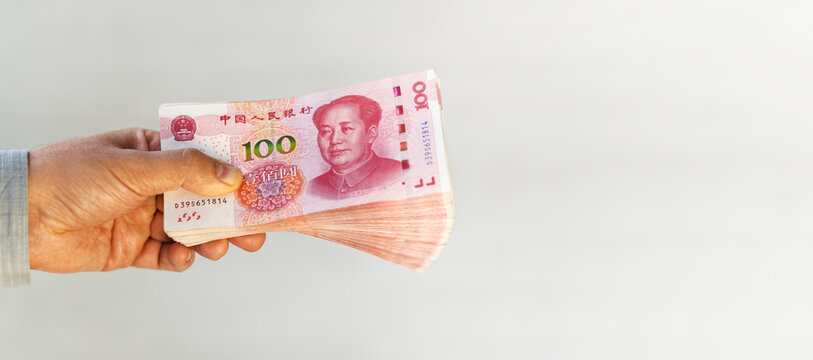 a man holds Chinese yuan in his hand on a white background,. The boss pays the salary. The concept of bribery and corruption, giving money. Businessman with Chinese yuan.