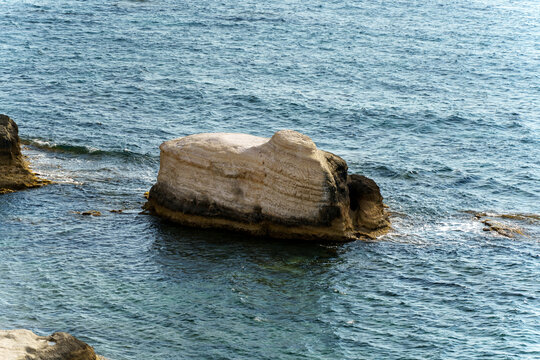 Large coastal rock formation along serene water at midday, captured in a coastal landscape - Powered by Adobe