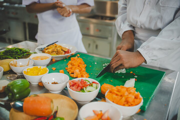 Chef student chopping fresh vegetables with knife during culinary training in professional kitchen