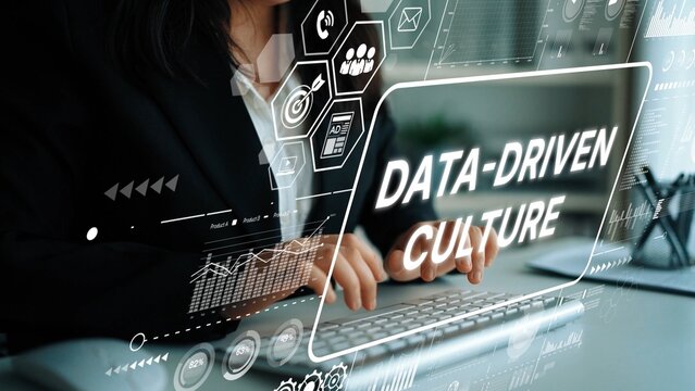 Businesswoman Typing on Laptop with Data-Driven Culture Concept Overlaid in Modern Office Environment. Asymptotic smart data analytic.