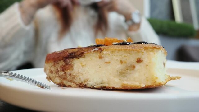 A girl in a cafe is eating dessert and drinking cappuccino, chatting on social media. A woman in casual clothes is sitting in the cafe, holding a smartphone in her hand and looking at it. 