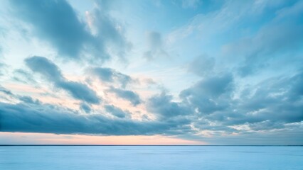 Fototapeta premium Vast Snowy Field Under a Dramatic Sky with Soft Sunset Hues Across the Horizon