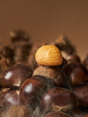 Close up of peeled yellow roasted chestnut placed on top of hot smoking chestnut pile