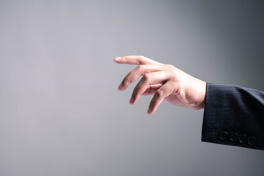 Close-up of a man's hand in a business suit reaching out or pointing on gradient background. Ideal for representing virtual interaction, touch command, innovation, or futuristic technology concepts.