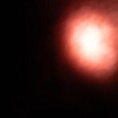 Abstract Dark Black Background with a Bright, Glowing Red Light Spot or Flare, Creating a Dramatic and Intense Effect