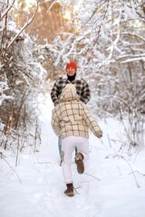 Father and daughter playing and enjoying the snow in a winter forest. Concept of family joy, warm emotions, childlike happiness, and fun winter activities outdoors.