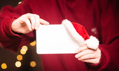 white sheet of paper copy space in a woman's hand against the background of New Year's bokeh