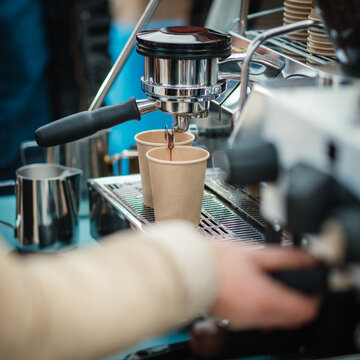 Barista bereitet Espresso in Pappbechern zu
