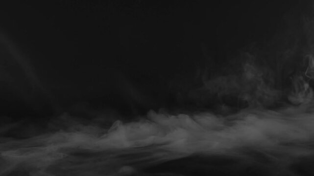 Low lying white smoke drifting on a dark surface mist