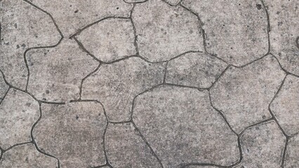 Top-down view of a weathered stone floor texture. Gray concrete pavement with an abstract mosaic pattern suitable for background, wallpaper, or architectural rendering