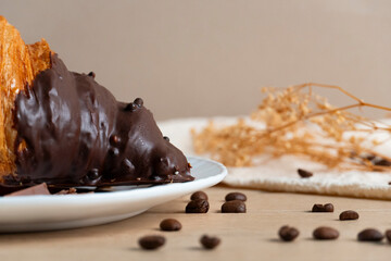 Chocolate-dipped croissant with coffee beans on a plate