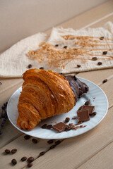 Chocolate-dipped croissant with coffee beans on a plate