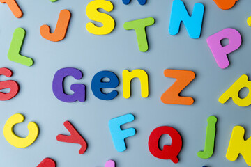 The phrase GEN Z is spelled out in colorful wooden letters scattered on a gray background. Modern generation, digital natives, youth culture, demographics, and future trends concept.