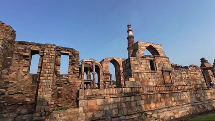 Architectural Heritage of Delhi: The Majestic Minaret, Surrounded by the Weathered Pillars and Fragmented Structures of the Old Mosque, Emphasizing the Scale and Grandeur of the Site.