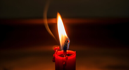 Red candle flame burning with smoke on dark background