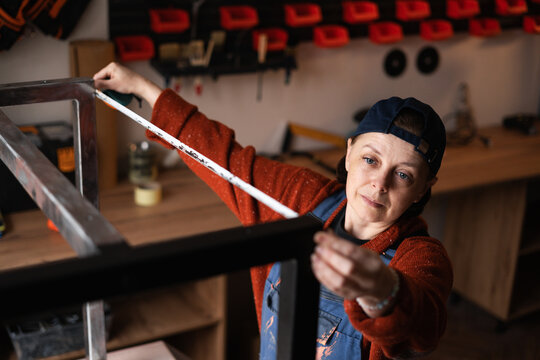 Handyman measuring metal legs in workshop with tape measure during furniture assembly. Concept of furniture making - Powered by Adobe