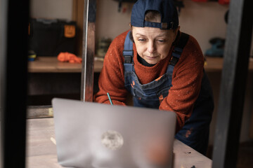 Business woman or Craftswoman working using a laptop in the garage. Mechanic at workshop.