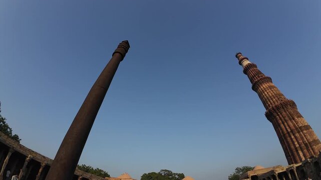 Historic View of the Qutub Minar Minaret alongside the Ancient Rust-Resistant Iron Pillar in the UNESCO World Heritage Complex of New Delhi India