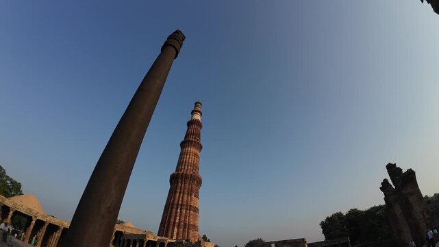 Historic View of the Qutub Minar Minaret alongside the Ancient Rust-Resistant Iron Pillar in the UNESCO World Heritage Complex of New Delhi India