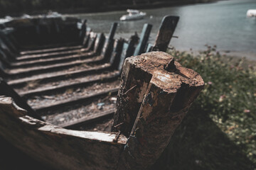 A wooden boat is sitting on the shore with a large log sticking out of it