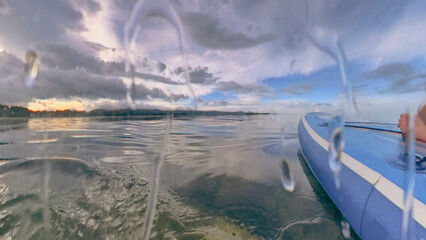 Blue paddleboard for paddle surfing on a cloudy sunset sea shore landscape in Chaweng Beach, Ko Samui, Thailand