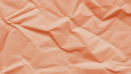 Closeup of crumpled peach paper texture with dramatic lighting and deep shadows