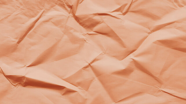 Closeup of crumpled peachcolored paper texture with deep folds and shadows
