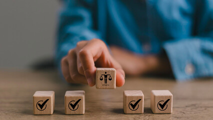 Ethical Assessment Concept. Placing wooden blocks with icons including checkmarks and a symbol of ethics, representing the evaluation and validation of ethical standards. Effective compliance.