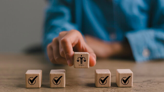 Ethical Assessment Concept. Placing wooden blocks with icons including checkmarks and a symbol of ethics, representing the evaluation and validation of ethical standards. Effective compliance.