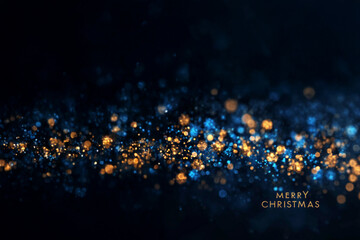 Texte en anglais « Merry Christmas » sur fond bleu nuit lumineux avec flares dorés et bokeh scintillant créant une ambiance festive de Noël et de fêtes de fin d’année avec espace négatif copyspace
