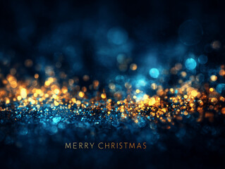 Texte en anglais « Merry Christmas » sur fond bleu nuit lumineux avec flares dorés et bokeh scintillant créant une ambiance festive de Noël et de fêtes de fin d’année avec espace négatif copyspace