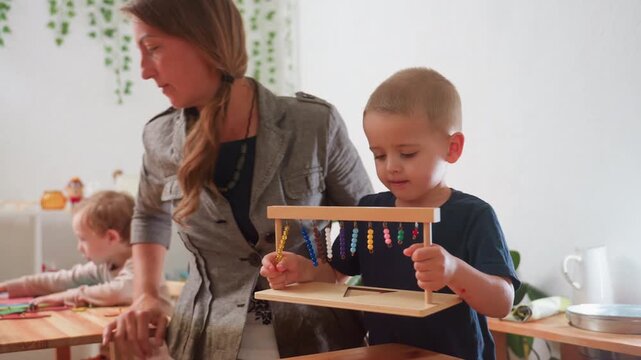 Care giver instruct child holding wooden abacus to return it, while other children remain engaged in classroom activities, capturing educational moment of early childhood learning