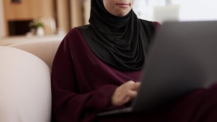 Arab woman in traditional hijab typing on laptop, freelance work from home