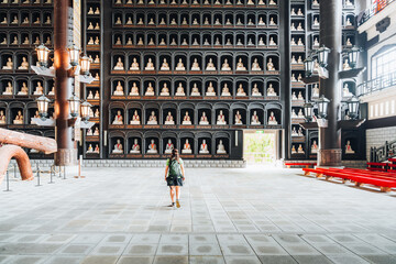Tourist with backpack explores a grand temple hall adorned with many Buddha statues